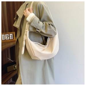 Detailed view of large cream crescent shoulder bag with wide adjustable strap on model