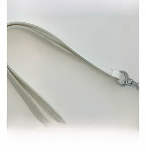 Detail of white leather tote bag handle with silver metal rings and reinforced stitching