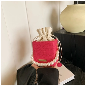 Close-up of fuchsia lace bucket bag with pearl handle and drawstring inner lining