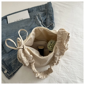 Detailed top view of beige ruffled nylon cloud bag with bow handle and zip closure