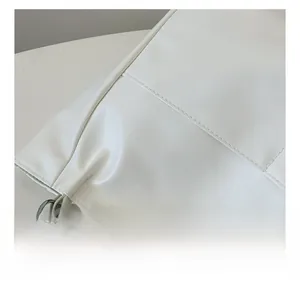 Detail view of the fine stitching and silver metal chain strap on a white tote bag