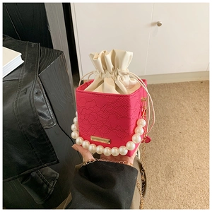 Detail of rose pink lace box bag with large pearl handle and golden chain strap