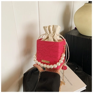Detail der rosaroten Perlgrifftasche mit Spitzenstruktur und goldener Kette