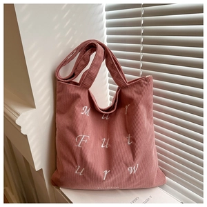 Macro detail of pink corduroy tote bag featuring white embroidery and striped texture