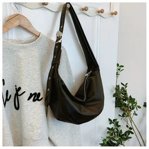 Detail of black hobo bag with wide adjustable strap and silver metal grommets