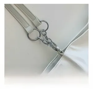 Detail of white leather tote bag showing silver metal chain rings and shoulder strap attachments