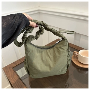 Detail of army green nylon shoulder bag with drawstring side pockets and ruched strap