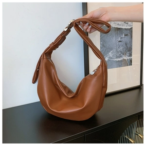 Detail of brown hobo bag with adjustable silver buckle and smooth faux leather texture