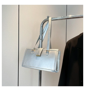 Detail der silbernen rechteckigen Handtasche mit Hochglanz-Finish und Goldbeschlägen