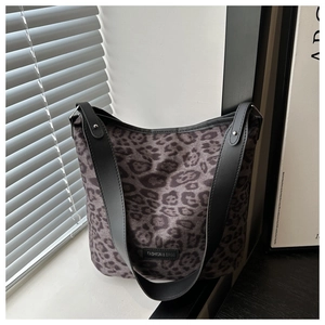 Detail of leopard print bucket bag with wide black shoulder strap and metal rivets
