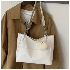 Detailed view of white tote bag with silver chain strap and beige plush charm pendant