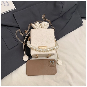Close-up of pearl handle and lace texture on chic crossbody bag with gold chain strap