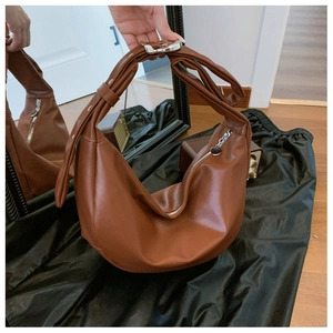 Detail of adjustable metal buckle and smooth matte texture on brown hobo shoulder bag