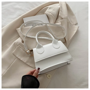 French chic style white leather handbag with gold hardware on a beige blazer setting