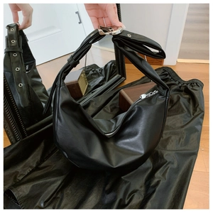 Detail of black crescent hobo bag with knotted handle and silver metal hardware