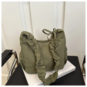 Close-up of olive green nylon cloud bag with quilted texture and ruched strap details
