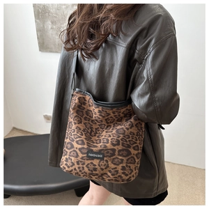 Vue détaillée d'un sac cabas léopard avec lanières en cuir noir sur une veste marron
