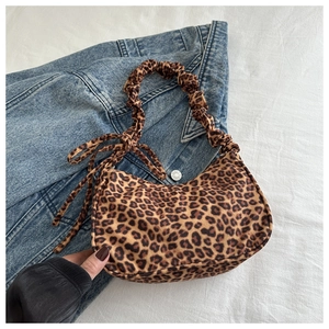 Detail of trendy leopard print underarm bag with pleated handle on denim jacket