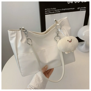 Detail of white faux leather tote bag with silver chain straps and plush charm