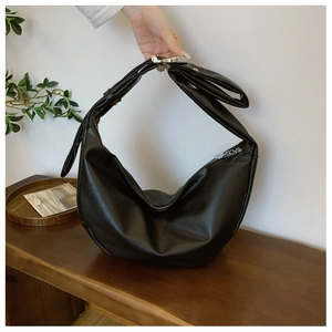 Detail of minimalist black PU leather half-moon bag with wide strap and metal zipper