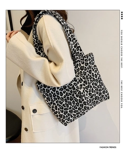 Model wearing large leopard print canvas tote bag with off-white wool coat indoors