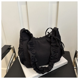 Close-up of a black pleated nylon shoulder bag with ruffled strap on a vintage chair