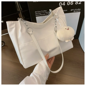 Detail of white tote bag with silver chain handle and plush cloud charm accessory