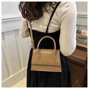 Rear view of khaki leather crossbody bag on model in a minimalist lifestyle setting