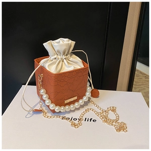 Detail of orange embossed lace bag featuring large pearl handle and silk drawstring lining