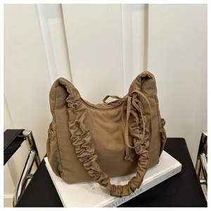 Detail of coffee brown nylon cloud bag featuring pleated straps and drawstring pockets