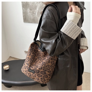 Detail of leopard print faux suede bucket bag with black strap and fashion label