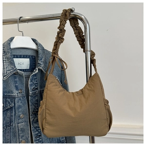 Detail of hobo bag with pleated scrunchie shoulder strap and decorative bow in brown nylon