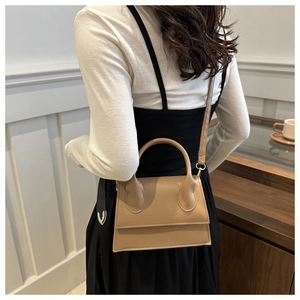 Detailed view of the tan leather mini handbag featuring a signature round top handle