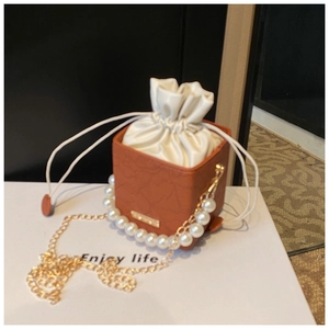 Detail of brown pebbled leather mini bucket bag with pearl handle and satin drawstring inner