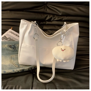 Close-up of white PU leather tote bag with functional front pocket and cute plush charm