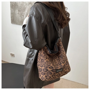 Detail of suede leopard print tote bag with black fashion label on the front side