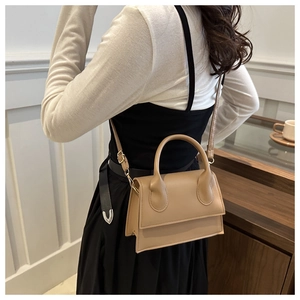 Detail of khaki square crossbody bag featuring a top handle and adjustable shoulder strap