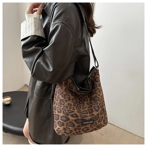 Detail of leopard print tote bag with black shoulder strap and fashion label on canvas