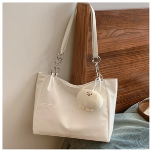 Detail of white PU leather tote with silver metal chain strap and plush fish charm