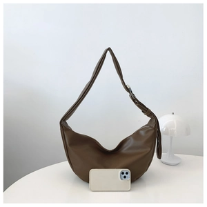 Detail of minimalist dark brown crescent shoulder bag with smooth faux leather texture