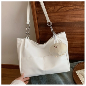 Detail of white tote bag featuring chain strap, front pockets, and plush cloud charm