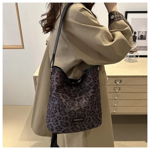 Détail du sac hobo à motif léopard avec bandoulière en cuir porté sur un trench-coat