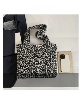 Detail view of large leopard print tote bag showing size scale with tablet and phone