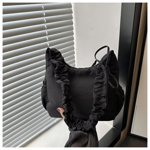 Close-up of black nylon handbag featuring pleated ruffle strap and matte fabric texture