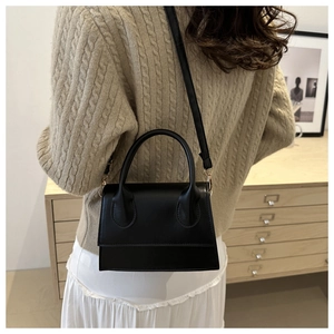 Retro black leather mini trapezoid handbag with rounded handle shown in cozy indoor setting