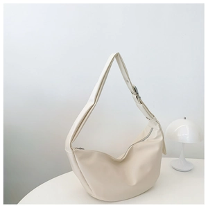 Minimalist beige hobo bag with silver metal buckle on a white table under soft light
