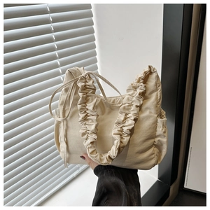 Detail of cream drawstring nylon cloud bag with ruched handle and pleated texture