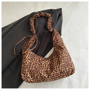 Detail of trendy leopard print shoulder bag with ruched handle on a grey blazer backdrop