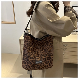 Detail of leopard print tote bag with brown shoulder strap and fashion label on canvas