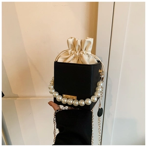Detail of contrast square bag with pearl handle, gold chain and drawstring closure